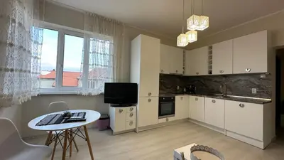 a kitchen with white cabinets and a table and a window at Скобелев 48 in Sofia