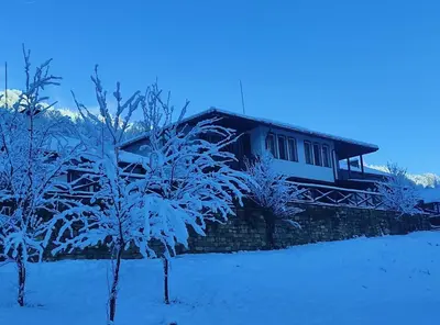a house covered in snow with trees in front of it at Къща за гости Лъките in Divchovoto