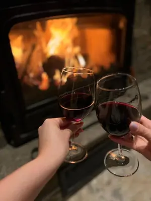 two people holding wine glasses in front of a fireplace at Къща за гости Лъките in Divchovoto