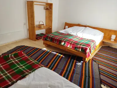 a bedroom with two beds and a rug at Калиновата къща in Stoykite