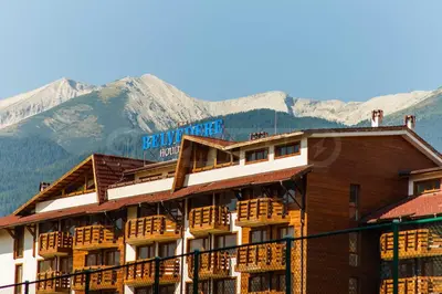 a hotel building with mountains in the background at Pirin's Hidden Gem BB & SKI & SPA in Bansko