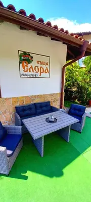 a patio with a table and chairs and a sign at Guest house Elora in Chiflik