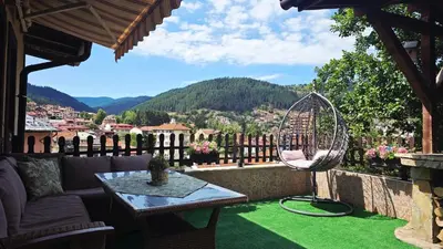 a patio with a table and a chair on a green lawn at Guest House Chepelare in Chepelare