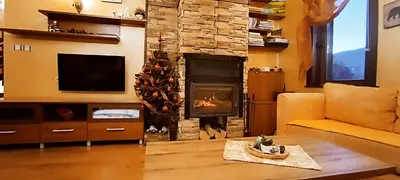 a living room with a fireplace and a christmas tree at Guest House Chepelare in Chepelare