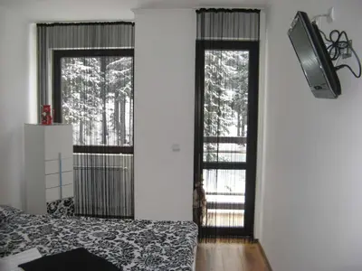a bedroom with two windows and a bed and a tv at Stenata Boutique Apartments in Pamporovo