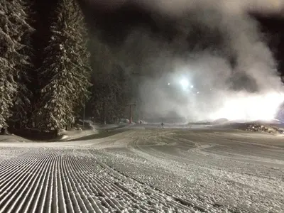 a snow covered road at night with smoke in the distance at Stenata Boutique Apartments in Pamporovo
