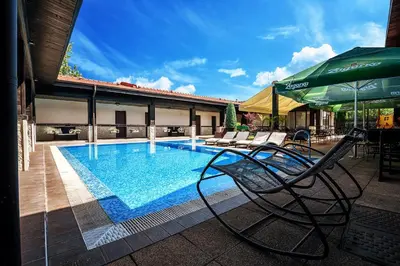 a pool with chairs and an umbrella next to a building at Complex Jitari in Zhitnitsa