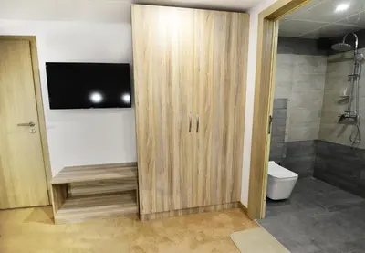 a bathroom with a toilet and a television on a wall at Hit Hot House in Sandanski
