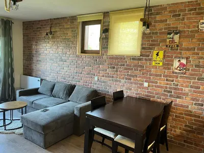 a living room with a couch and a table and a brick wall at Forest View Apartment C34 Bansko in Bansko