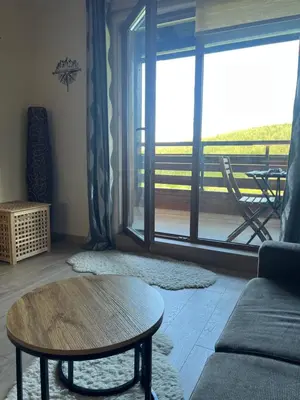 a living room with a table and a large window at Forest View Apartment C34 Bansko in Bansko
