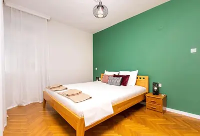 a bedroom with a large bed with a green wall at Central Family Apt Fuzzy Muzzy 2 bedrooms MU University in Plovdiv