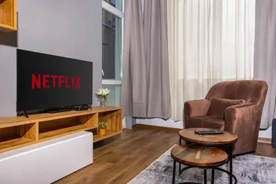 a living room with a television and a chair at Hidden Gem in the Heart of Plovdiv in Plovdiv