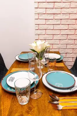 a wooden table with plates and wine glasses on it at Hidden Gem in the Heart of Plovdiv in Plovdiv