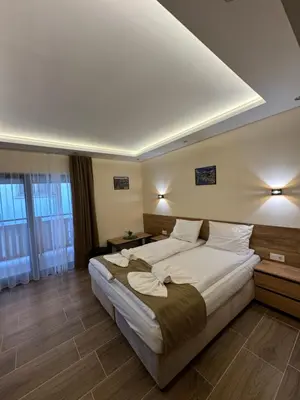 a hotel room with a bed with white sheets and pillows at Къща Александра 2 in Dobrinishte