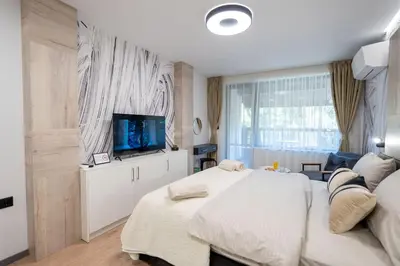 a bedroom with a large bed and a flat screen tv at Arni Aparts 1 in Velingrad