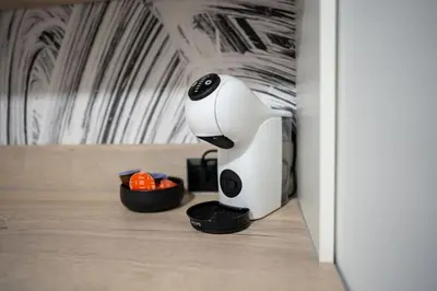 a white and black coffee maker next to a bowl of oranges at Arni Aparts 1 in Velingrad