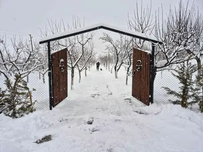 a fence covered in snow with a person in the distance at Алпийска вила в полите Рила in Resilovo