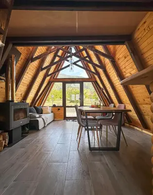 a room with a table and chairs in a attic at Алпийска вила в полите Рила in Resilovo