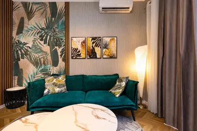 a green couch in a living room with paintings at The Urban Nest-2BD Apartment with a Terrace by Flat Mаnager in Plovdiv