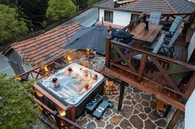 a group of people in a swimming pool with an umbrella at Spa Villa Mezinska Jacuzzi Sauna in Shiroka Lŭka