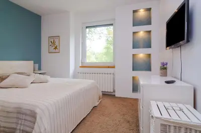 a bedroom with a white bed and a television at Spacious and modern apt, 6 guests, Central station, self check-in in Sofia