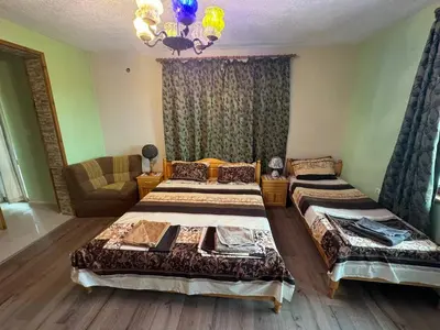 a bedroom with two beds and a couch and a chandelier at Пандова къща in Sandanski