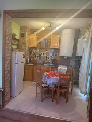 a kitchen with a table and chairs and a white refrigerator at Пандова къща in Sandanski