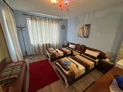 a room with two beds and a red rug at Пандова къща in Sandanski