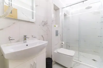 a white bathroom with a sink and a shower at LDV 13 Apartments Free private parking in Plovdiv