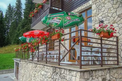 a balcony with an umbrella and chairs and flowers at Stream Spa Suite in Pamporovo