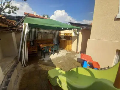 a patio with a table and a green umbrella at Къща за гости Съкровище in Panagyurishte