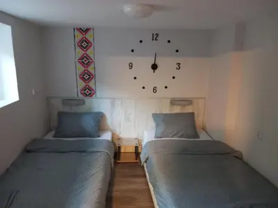 a room with two beds and a clock on the wall at Къща за гости Съкровище in Panagyurishte