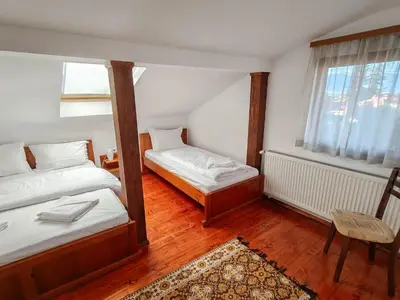 a bedroom with two beds and a chair and a window at Todeva House Hotel and Tavern in Bansko