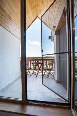 an open glass door with a table on a balcony at Alpin Penthouse 2 Bedroom with Fireplace and Mountain View in Bansko