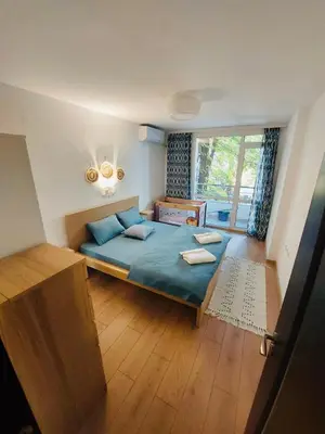 a bedroom with a bed with blue sheets and a window at Sky Hills 2 Apartment in Sandanski