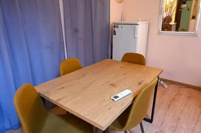 a wooden table with chairs and a white refrigerator at National Theatre Loft in Sofia