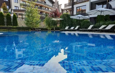 a swimming pool with chairs and umbrellas in a building at Apartment in Aspen Golf in Bansko