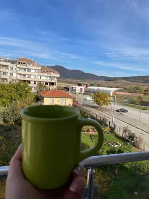 a person holding a green coffee cup on a balcony at Апартамент Димана in Hisarya