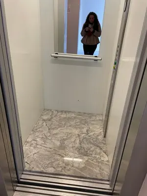 a woman taking a picture of a marble floor in a bathroom at Апартамент Димана in Hisarya