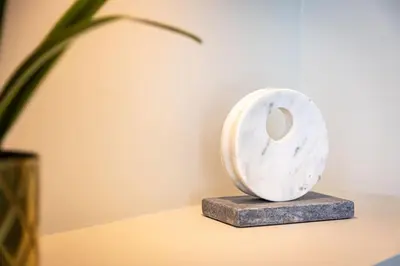 a white vase sitting on a table next to a plant at Olive Green Designer Apartment in Plovdiv