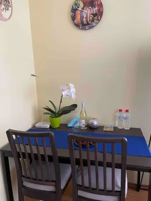 a blue table with two chairs and a clock on the wall at Blue Orchid Studio near airport & free parking in Sofia