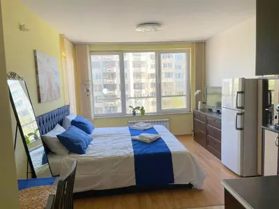 a bedroom with a bed with blue pillows and a refrigerator at Blue Orchid Studio near airport & free parking in Sofia