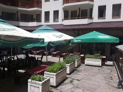 a patio with tables and umbrellas and plants at Villa Park Guest Apartments in Borovets