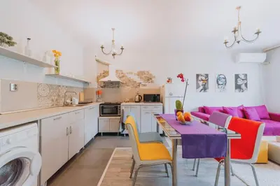 a kitchen and living room with a table and colorful chairs at Апартамент Веирас 2 in Velingrad