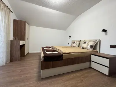 a bedroom with a large bed and a wooden floor at Вила Белият камък - Златоград in Zlatograd