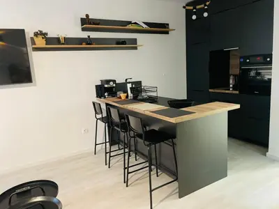 a kitchen with black cabinets and a counter with stools at Apartament-DEMIAN in Sofia