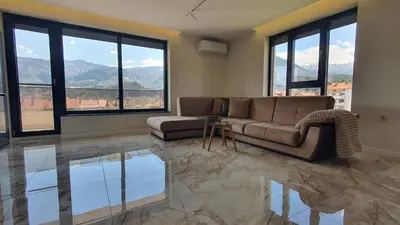 a living room with a couch and a table and windows at Panorama view apartment in Gotse Delchev