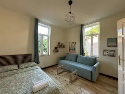 a bedroom with a bed and a couch and windows at Уютна къща в сърцето на София in Sofia