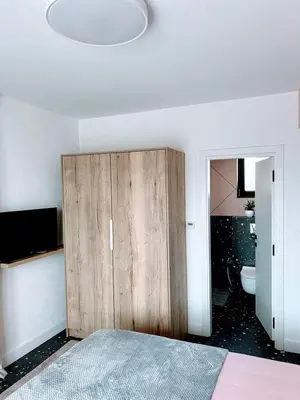 a bedroom with a wooden cabinet and a bathroom at Къща за гости Алегра in Garmen