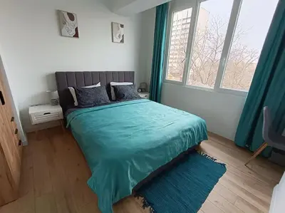 a bedroom with a bed with blue sheets and a window at Apartament Aleksandar Premium in Kyustendil